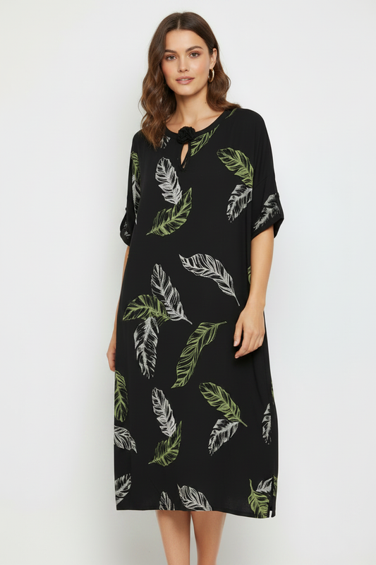 Model wearing black tropical leaf dress with tassel neckline